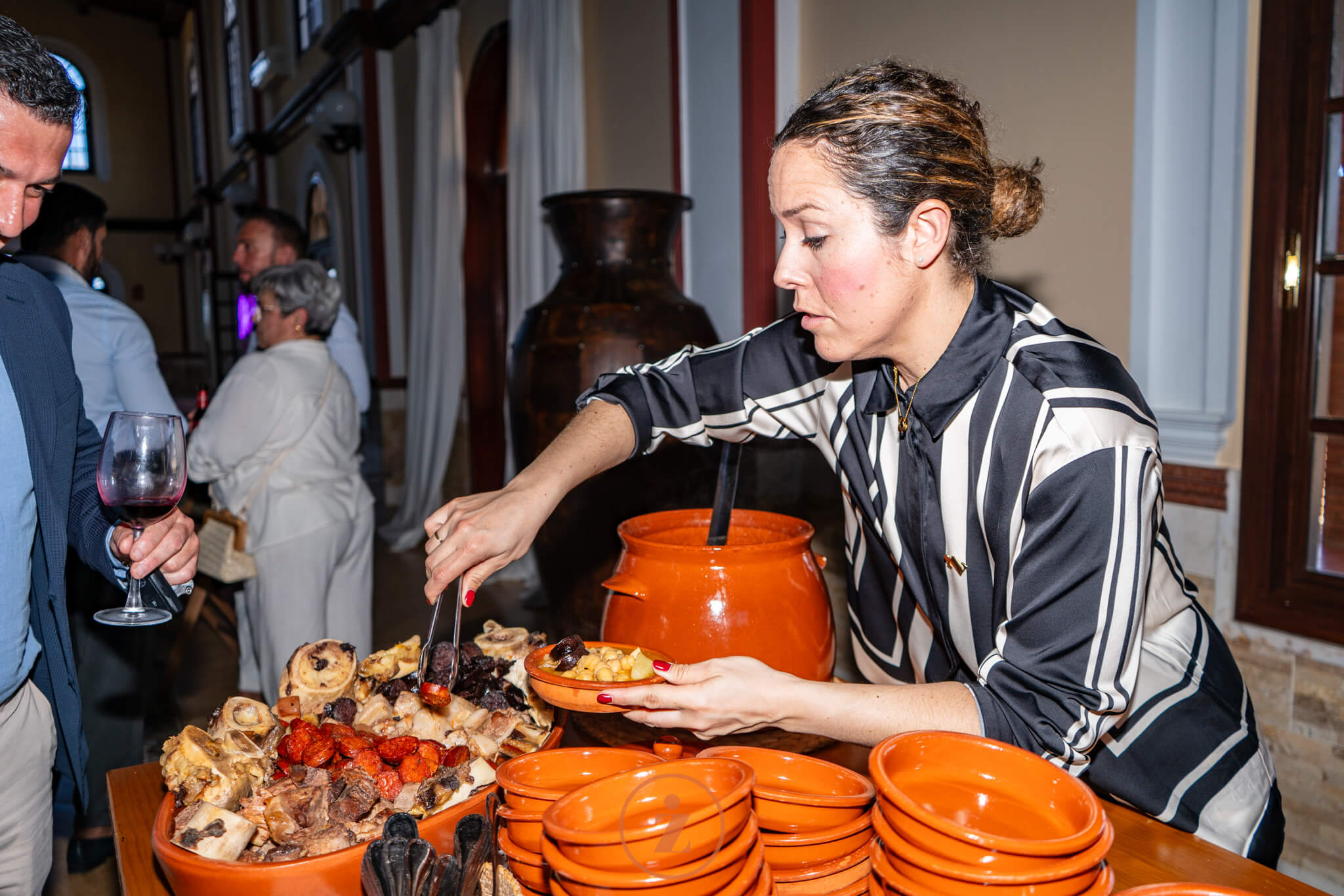 jefa de sala sirviendo cocido en platos de barro durante un evento de empresa